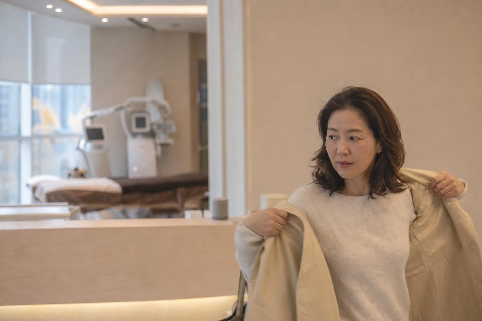 首爾江南診間裡，一位三十多歲的女性在鏡子前確認下顎線，醫師在旁說明消脂針療程