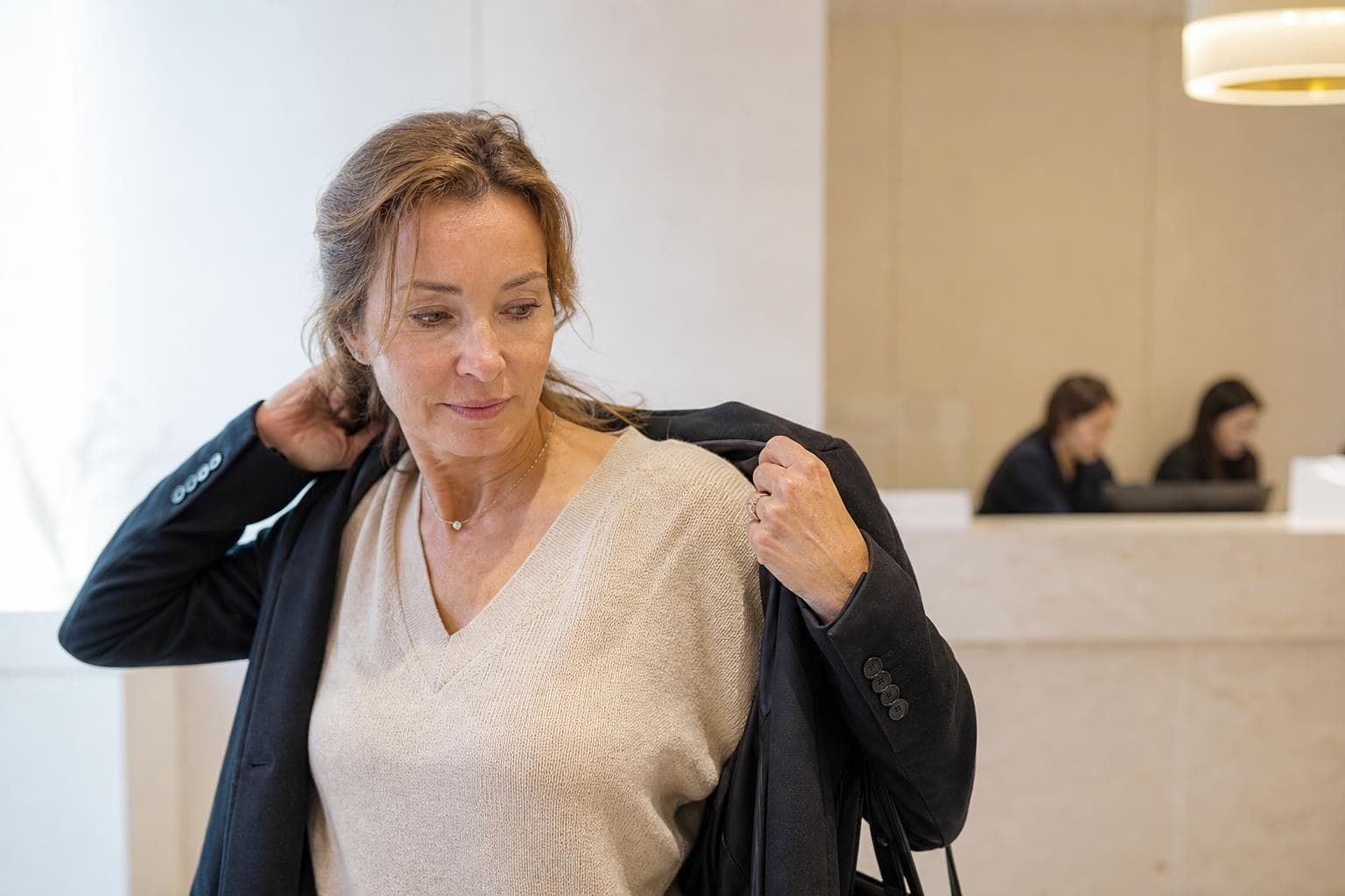 Close-up of a woman in her late thirties touching her cheek to feel skin texture, in a bright Seoul clinic room