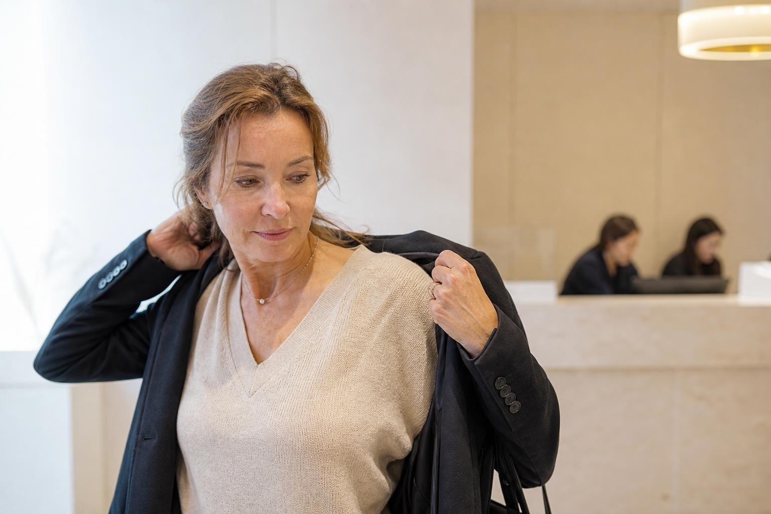 Close-up of a woman in her late thirties touching her cheek to feel skin texture, in a bright Seoul clinic room