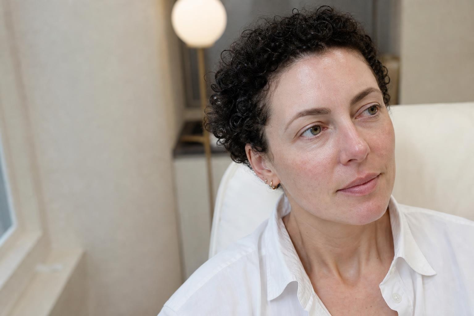 A woman in her late thirties with flushed cheeks and visible fine vessels, photographed in cool daylight